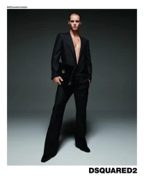Male model in a black suit holding a dark handbag against a grey seamless background for Dsquared2