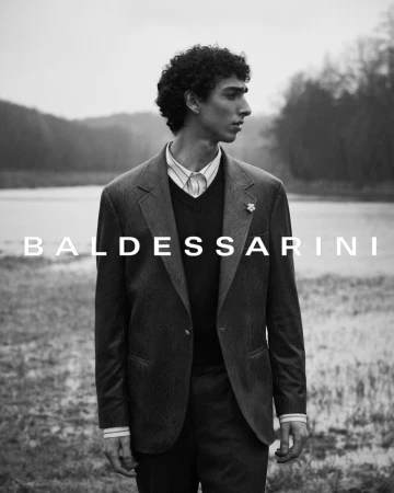 Monochrome portrait of a male model wearing a tailored suit jacket by a lake for Baldessarini Fall 2024 ad campaign.