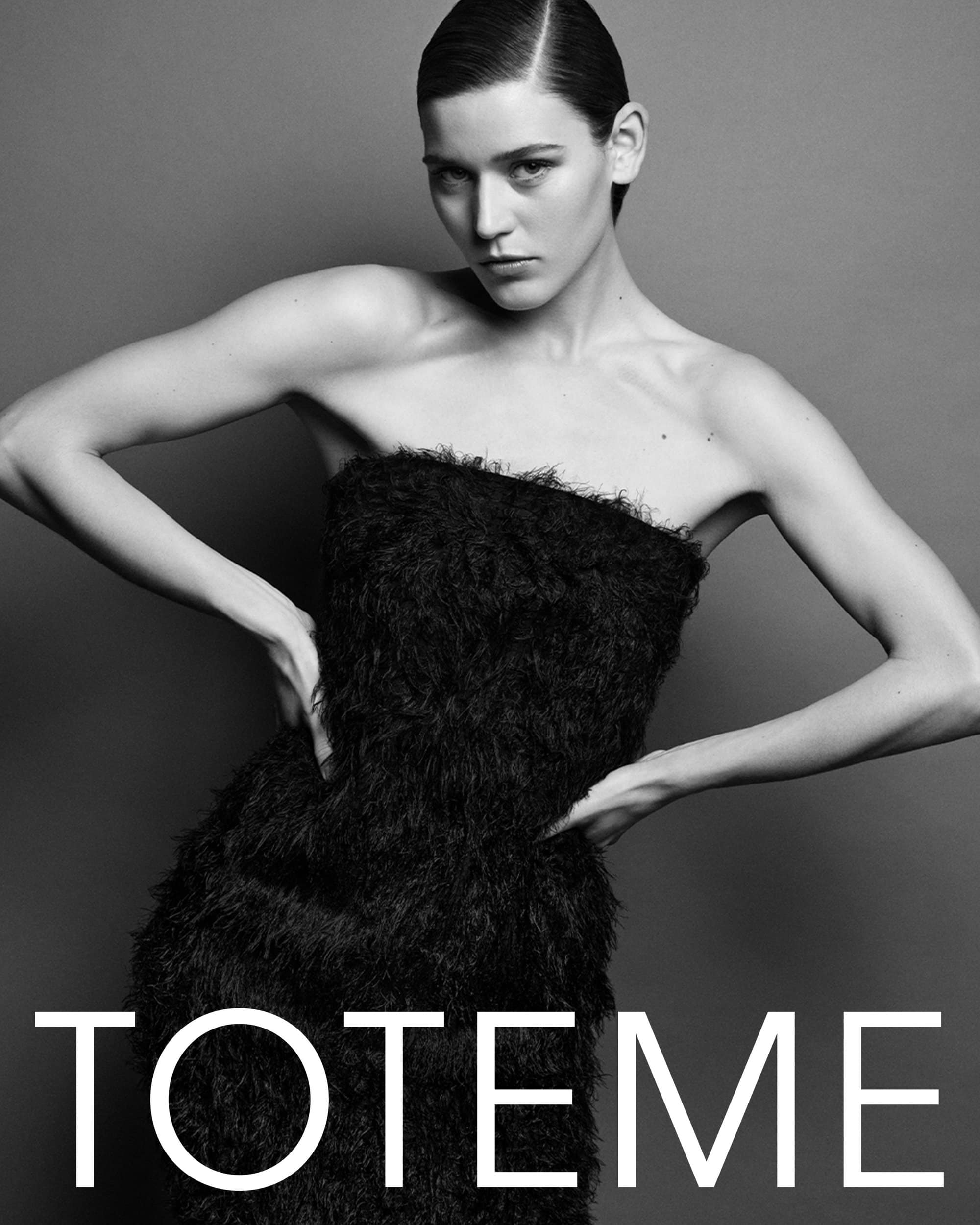 Model wearing a black strapless textured dress against a grey background with white text overlaid at the bottom