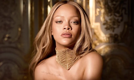 Portrait of Rihanna wearing a multi-strand gold pearl choker necklace with ornate gilded architecture in the background.