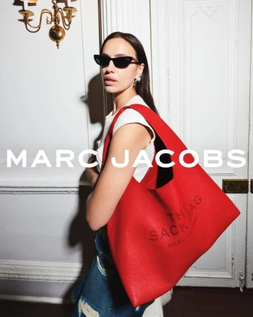 Model Irina Shayk wearing sunglasses holding a large red shoulder bag for Marc Jacobs Fall 2024 campaign