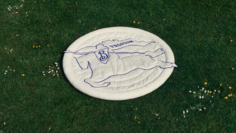 Round white quilted mat with embroidered blue Prorsum equestrian knight logo laid on green grass