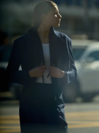 Model wearing a dark blue jacket and skirt set over a white top outdoors in New York City.