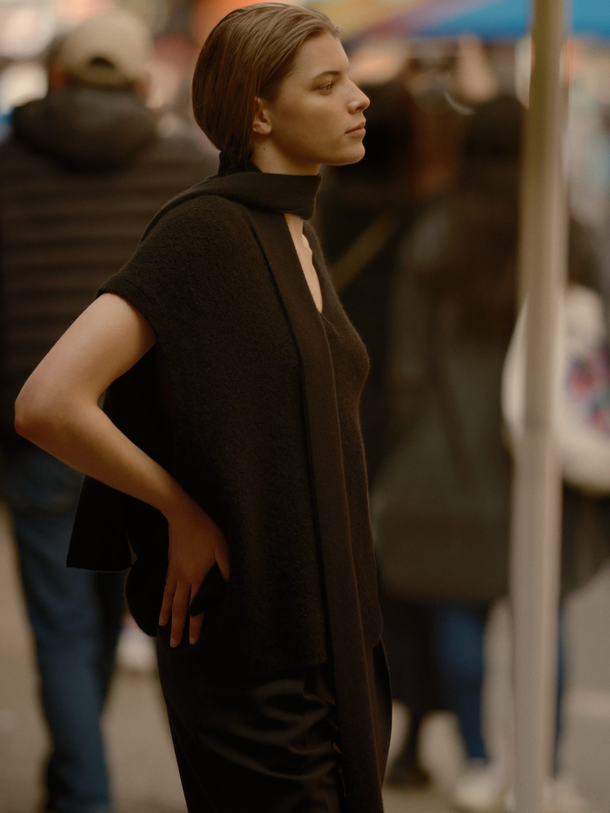 Woman in a black sleeveless top standing on a busy New York City street