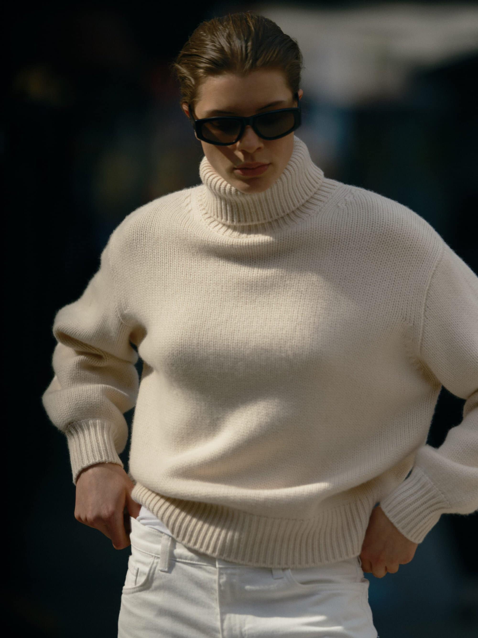 Model wearing a cream turtleneck sweater and dark sunglasses outdoors for the Soft Goat Fall 2024 campaign.