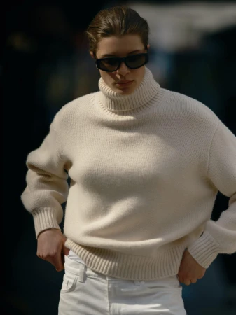 Model wearing a cream turtleneck sweater and dark sunglasses outdoors for the Soft Goat Fall 2024 campaign.