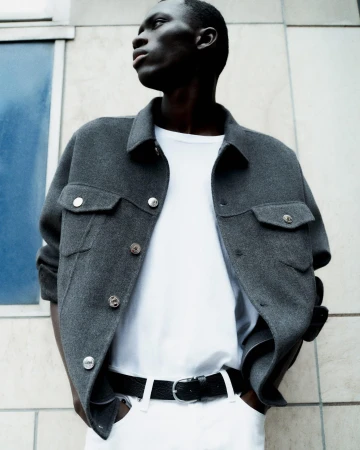 Black man wearing dark grey wool jacket and white t-shirt against building exterior