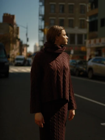 Model standing on a city street wearing a dark burgundy cable knit sweater and matching skirt.