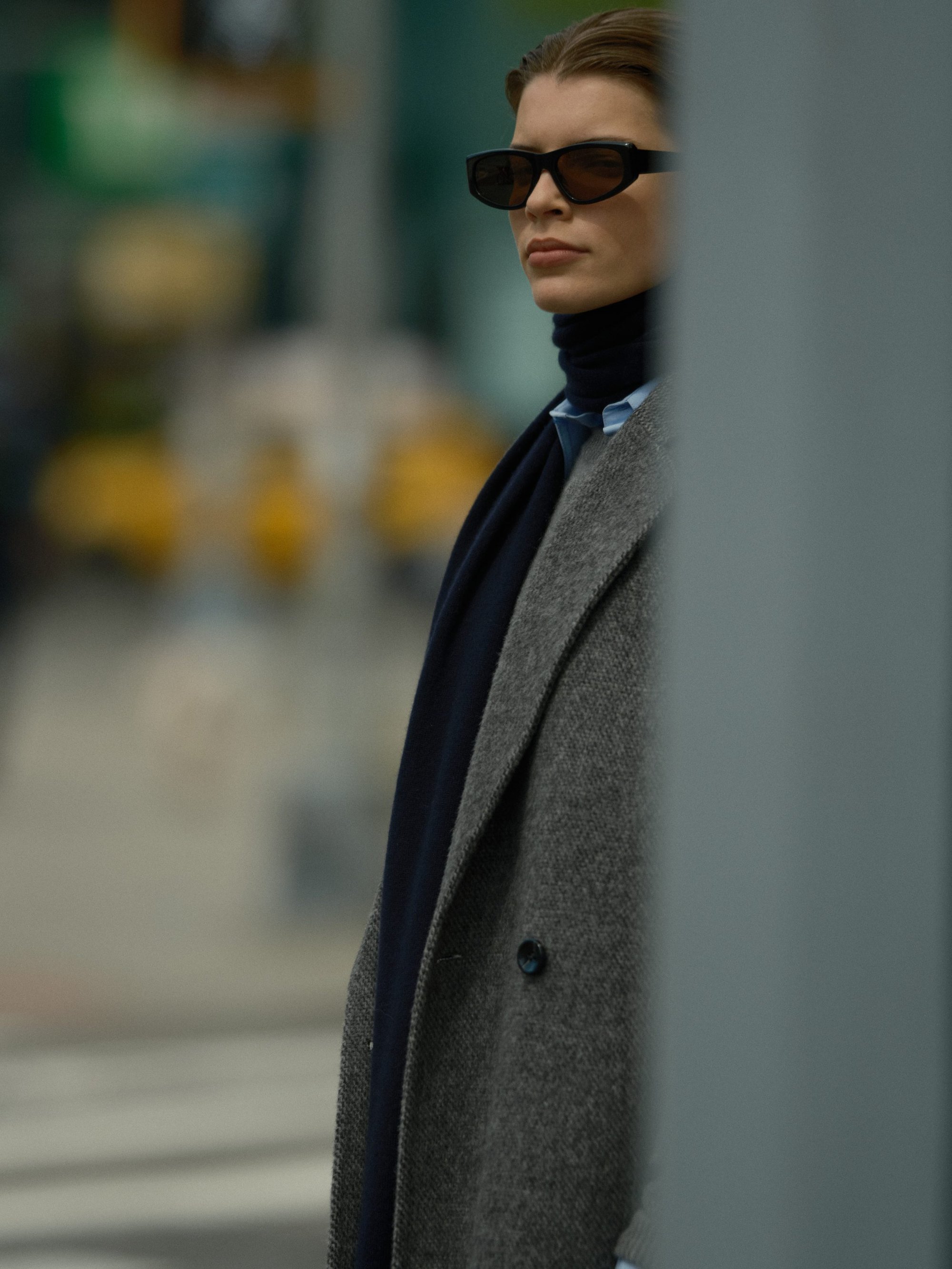 Model wearing dark sunglasses and a grey wool coat over a dark turtleneck for the Soft Goat Fall 2024 campaign in New York City.