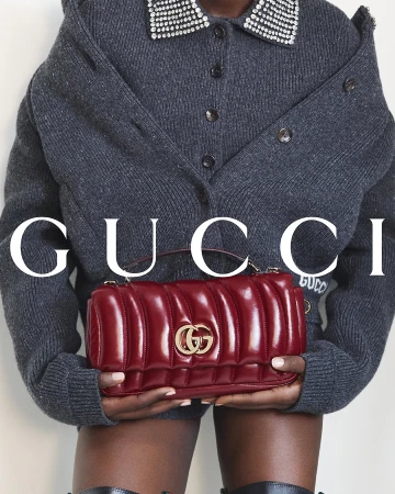 Model holding a quilted red leather handbag wearing a grey cardigan with crystal collar for Gucci Fall 2024 campaign