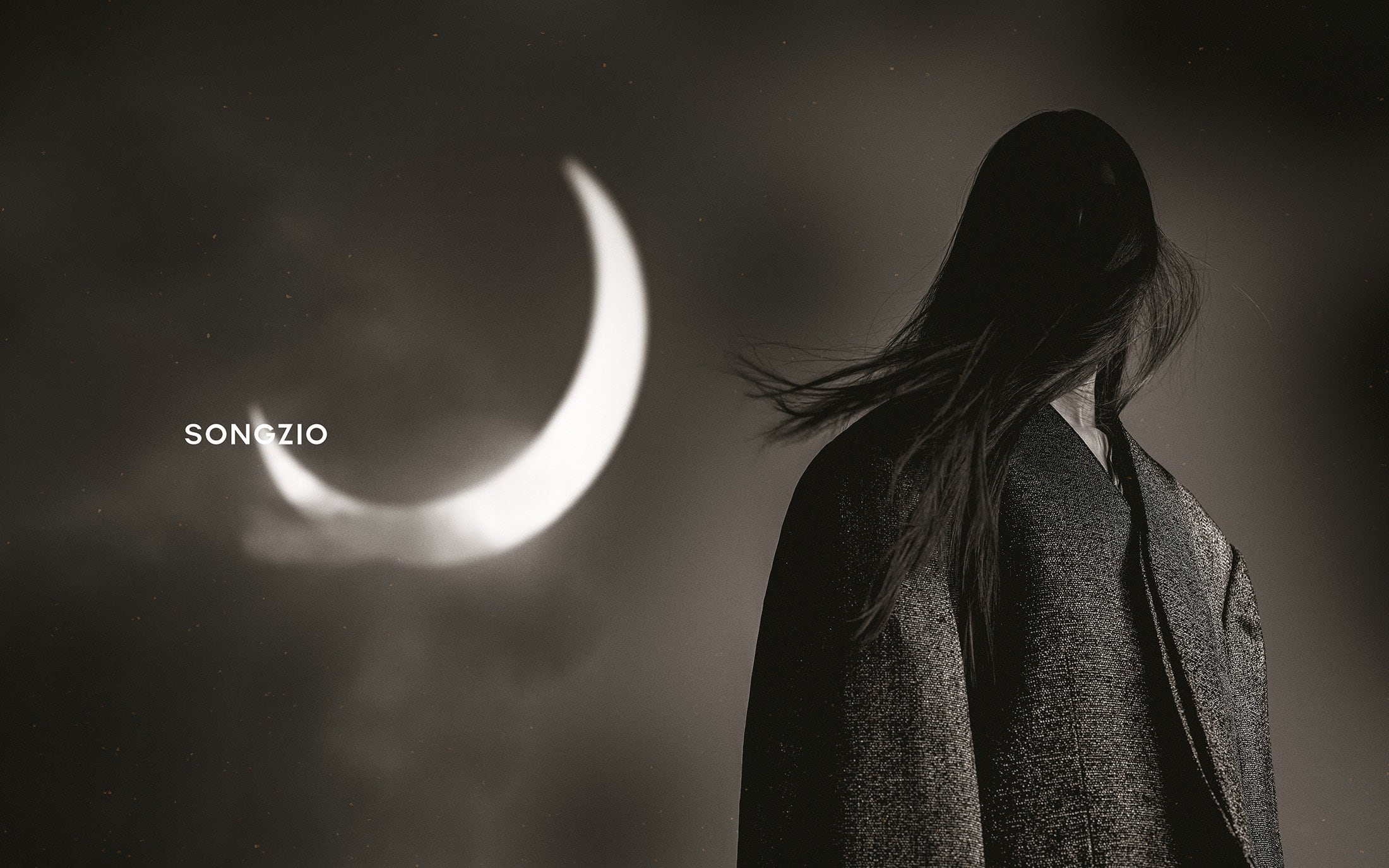 Monochrome portrait of a person with long dark hair wearing a dark jacket, facing away against a large glowing crescent moon background.