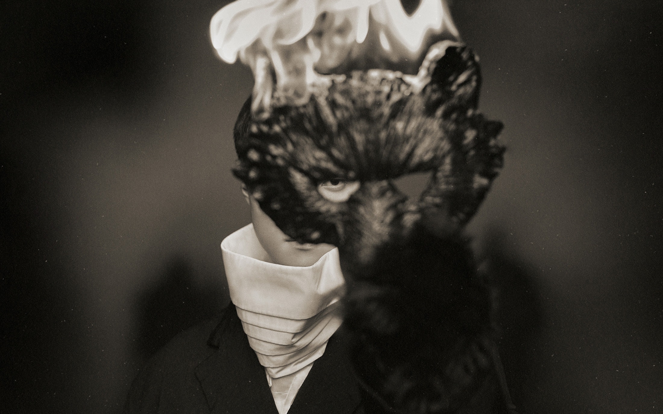 Model wearing a dark sculpted animal mask and white high-collared neckpiece for Songzio fall 2024 campaign