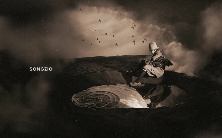 Monochrome image of a person wearing a bucket hat seated beside a pool of water under a cloudy sky with birds flying.
