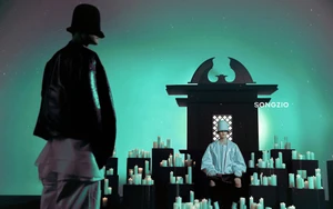 Two models in dark attire and hats on a green-lit stage surrounded by numerous burning candles for Songzio Fall 2024 campaign