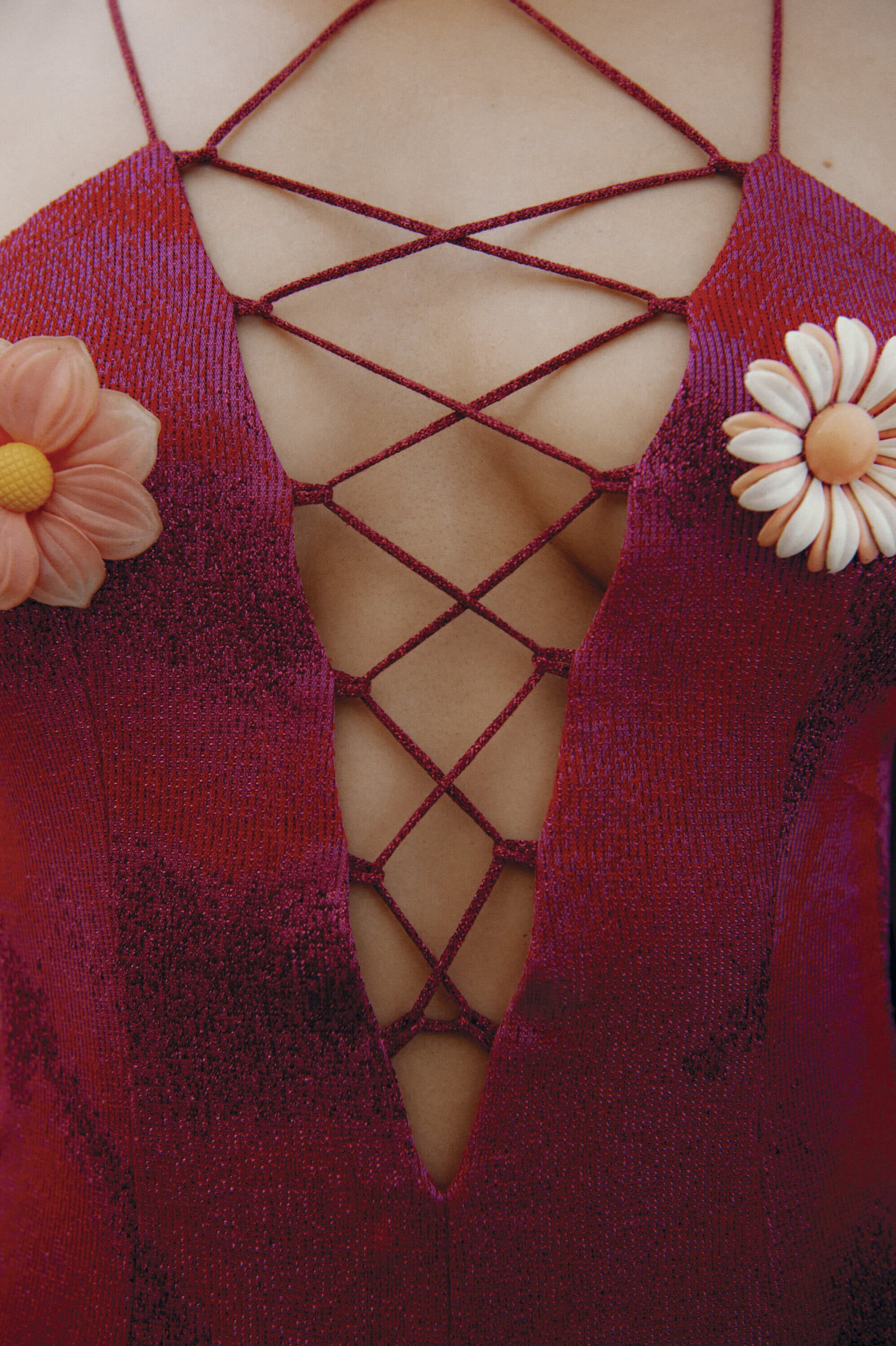 Close-up of a red lace-up dress adorned with two floral appliqués for Maccapani Fall 2024 Ad Campaign.