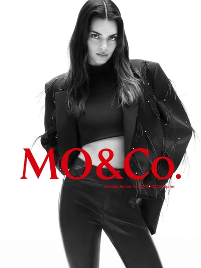 Kendall Jenner in a black blazer and leather trousers for mo.co NOIR 2024 campaign against a white backdrop.
