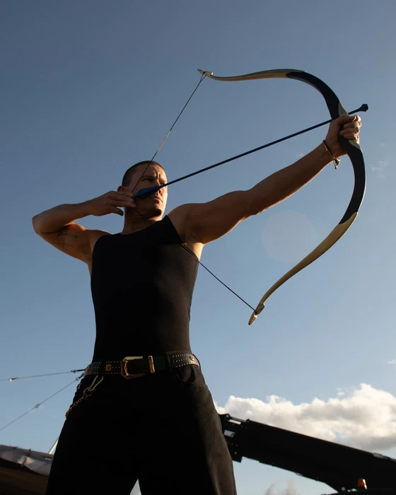 Channing Tatum pulling a recurve bow against a clear blue sky for Versace Eros Energy campaign