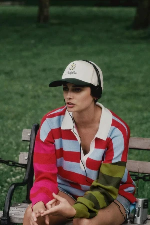 Woman wearing a striped sweater and cap seated on a park bench