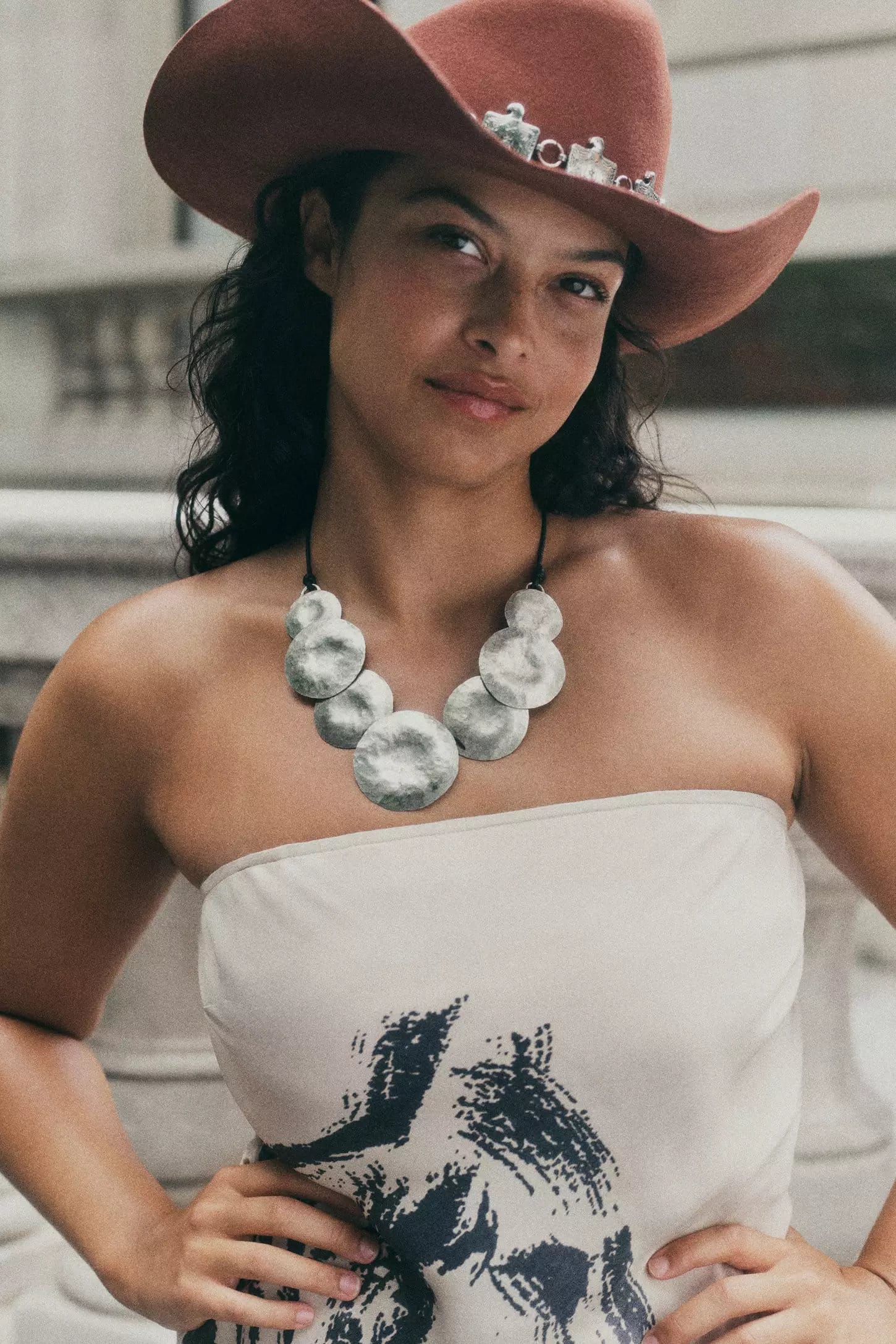 Model Devyn Garcia wearing a brown cowboy hat and silver pendant necklace in New York City for Anthropologie fall 2024 campaign