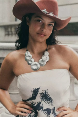 Model Devyn Garcia wearing a brown cowboy hat and silver pendant necklace in New York City for Anthropologie fall 2024 campaign