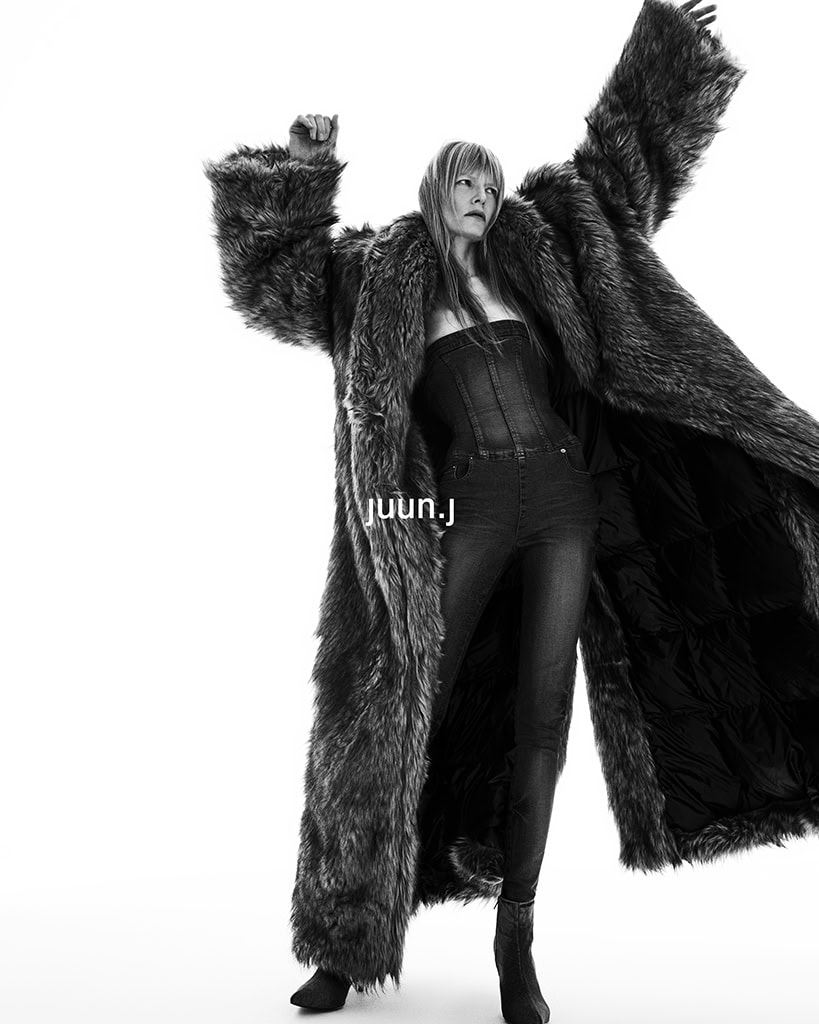 Kirsten Owen in a voluminous faux fur coat and denim jumpsuit for Juun.J Fall 2024 ad campaign against a plain background