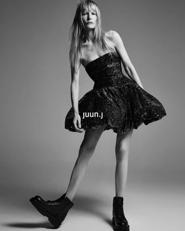 Model Kirsten Owen in a black sequin strapless mini dress and chunky boots against a grey seamless background