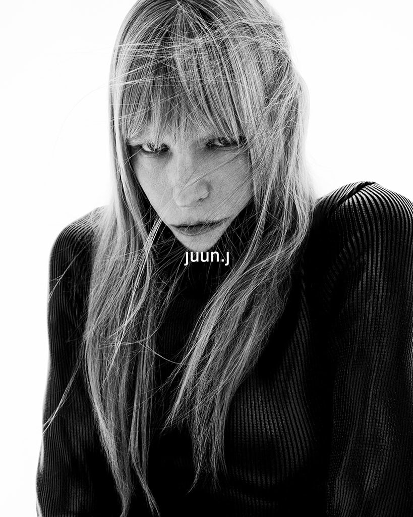 Model Kirsten Owen wearing a black ribbed turtleneck sweater against a bright white background for Juun.J