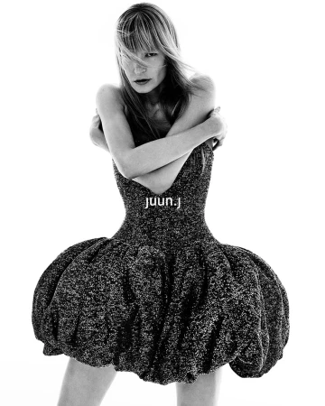 Kirsten Owen wearing a voluminous dark textured dress with crossed arms against a seamless white background for Juun.J