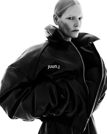 Model wearing an oversized black leather puffer jacket against a stark white background for Juun.J campaign