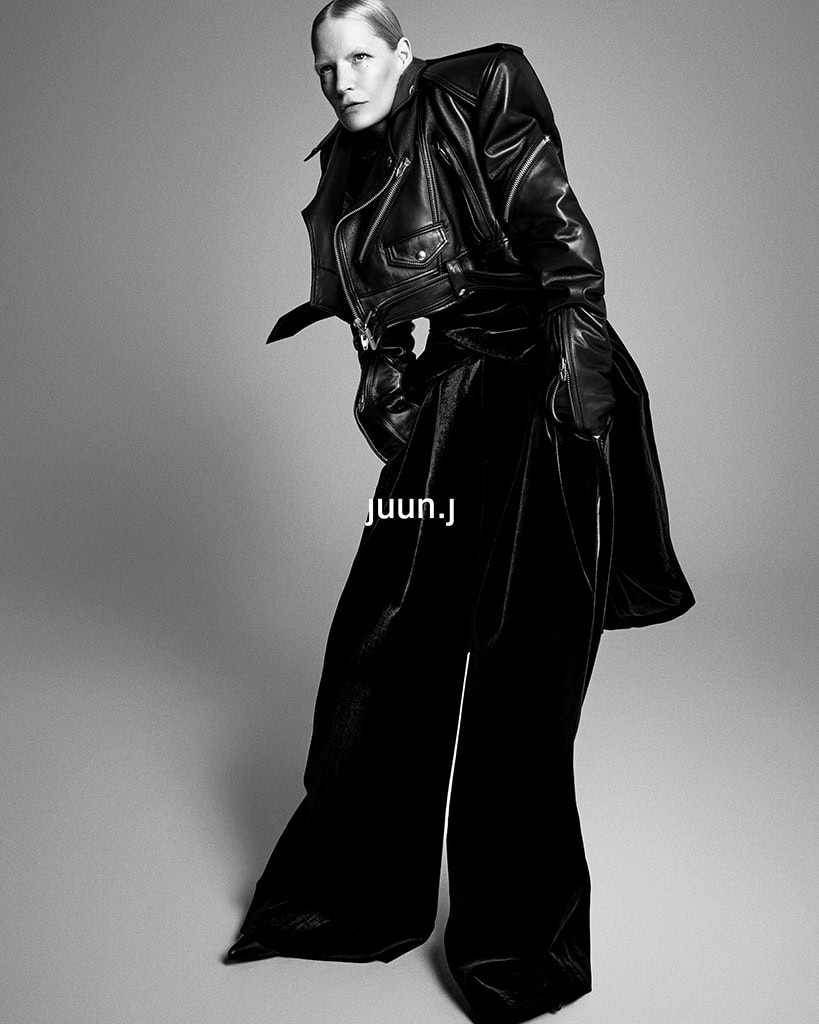 Model Kirsten Owen in a black leather jacket and wide trousers posing against a grey seamless studio backdrop for Juun.J.