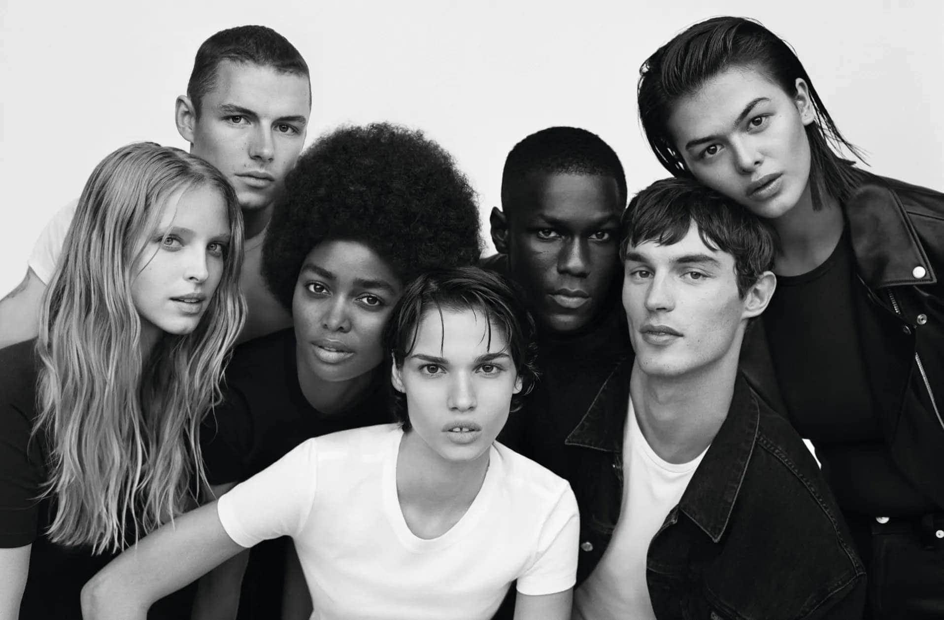 Black and white portrait of a group of diverse models posing together against a light background for Calvin Klein.