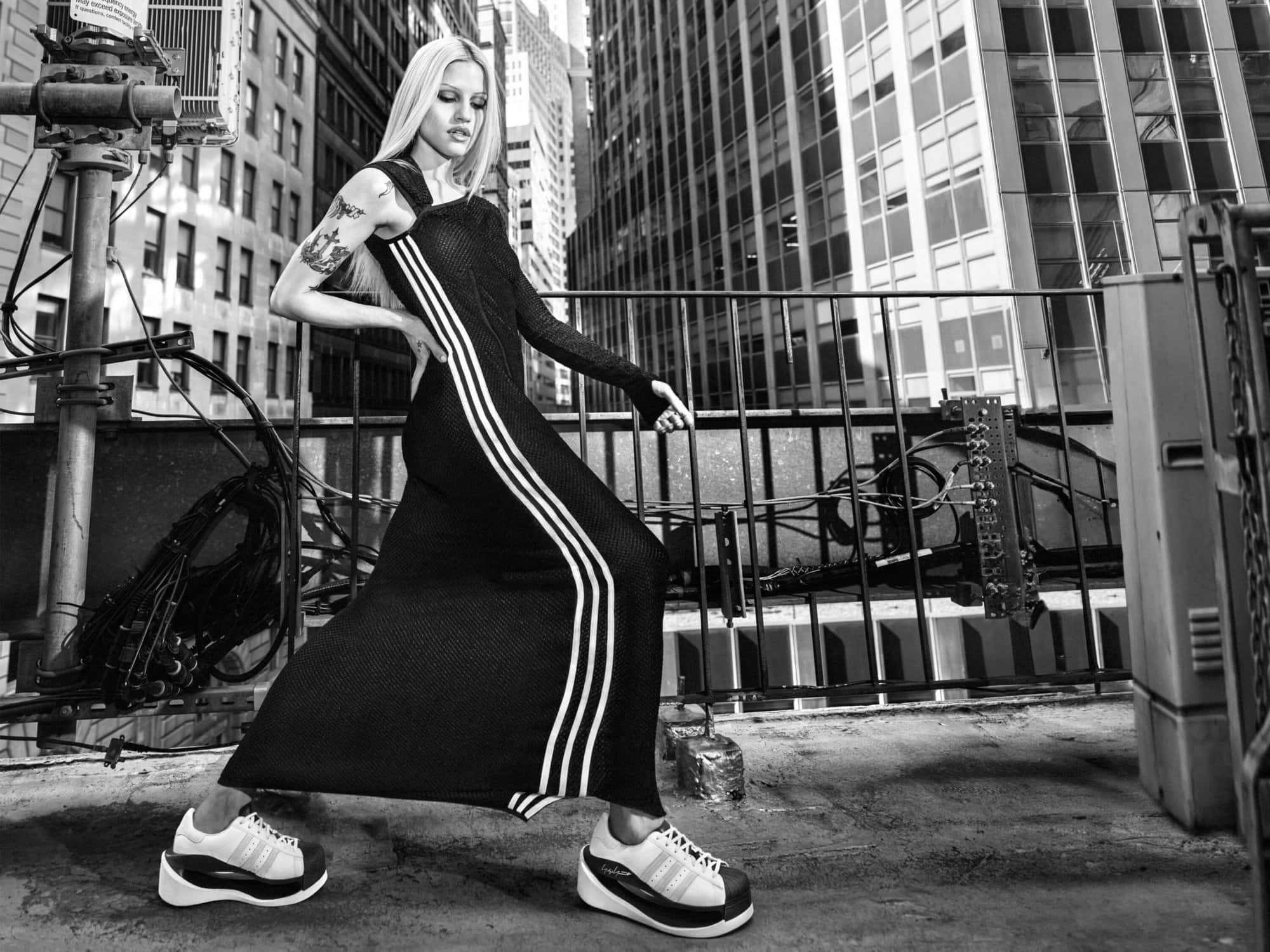 Model Gabbriette posing on an urban rooftop in New York City wearing a black Y-3 dress and sneakers for the Fall 2024 campaign.
