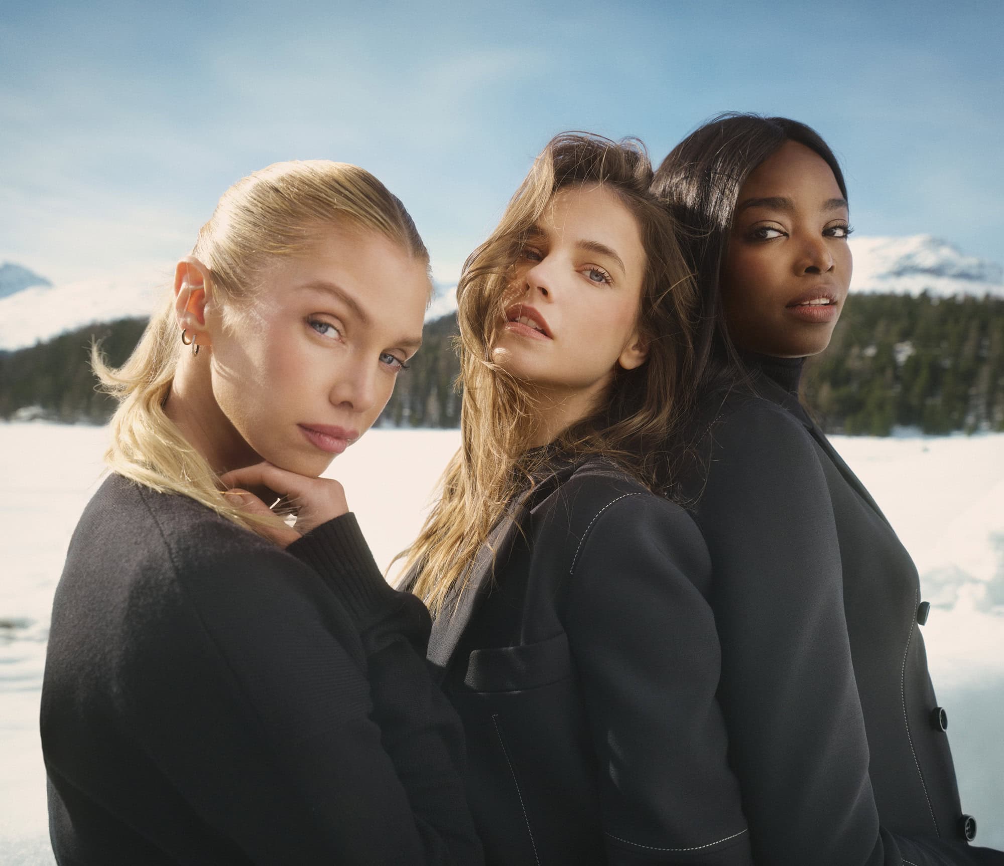 Three female models wearing black tailored jackets against a snowy mountain landscape for Ports 1961 fall ad campaign