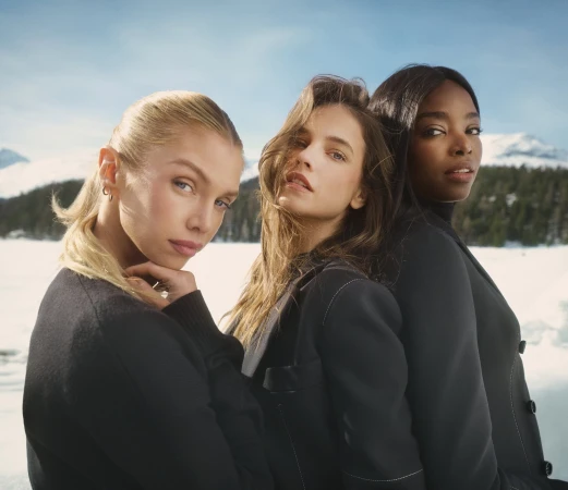 Three female models wearing black tailored jackets against a snowy mountain landscape for Ports 1961 fall ad campaign