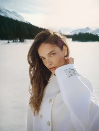 Model Barbara Palvin wearing a white coat outdoors against a snowy landscape for Ports 1961 ad campaign