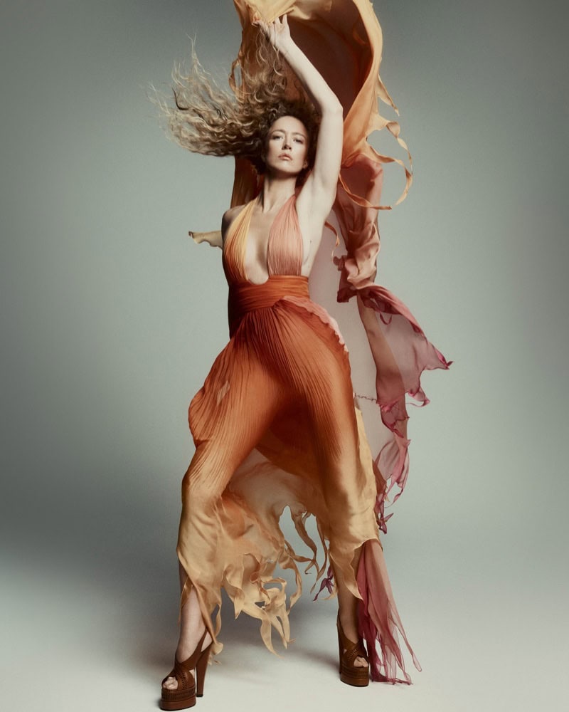 Model Raquel Zimmermann wearing a flowing gradient halter gown against a grey backdrop for Roberto Cavalli