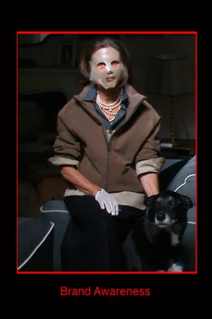 Woman wearing a face mask and brown jacket sitting on a sofa with a black dog for GR10K Incognito campaign.