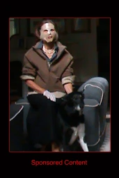 Person seated on a chair wearing a brown jacket and a face covering next to a dark dog in an indoor setting