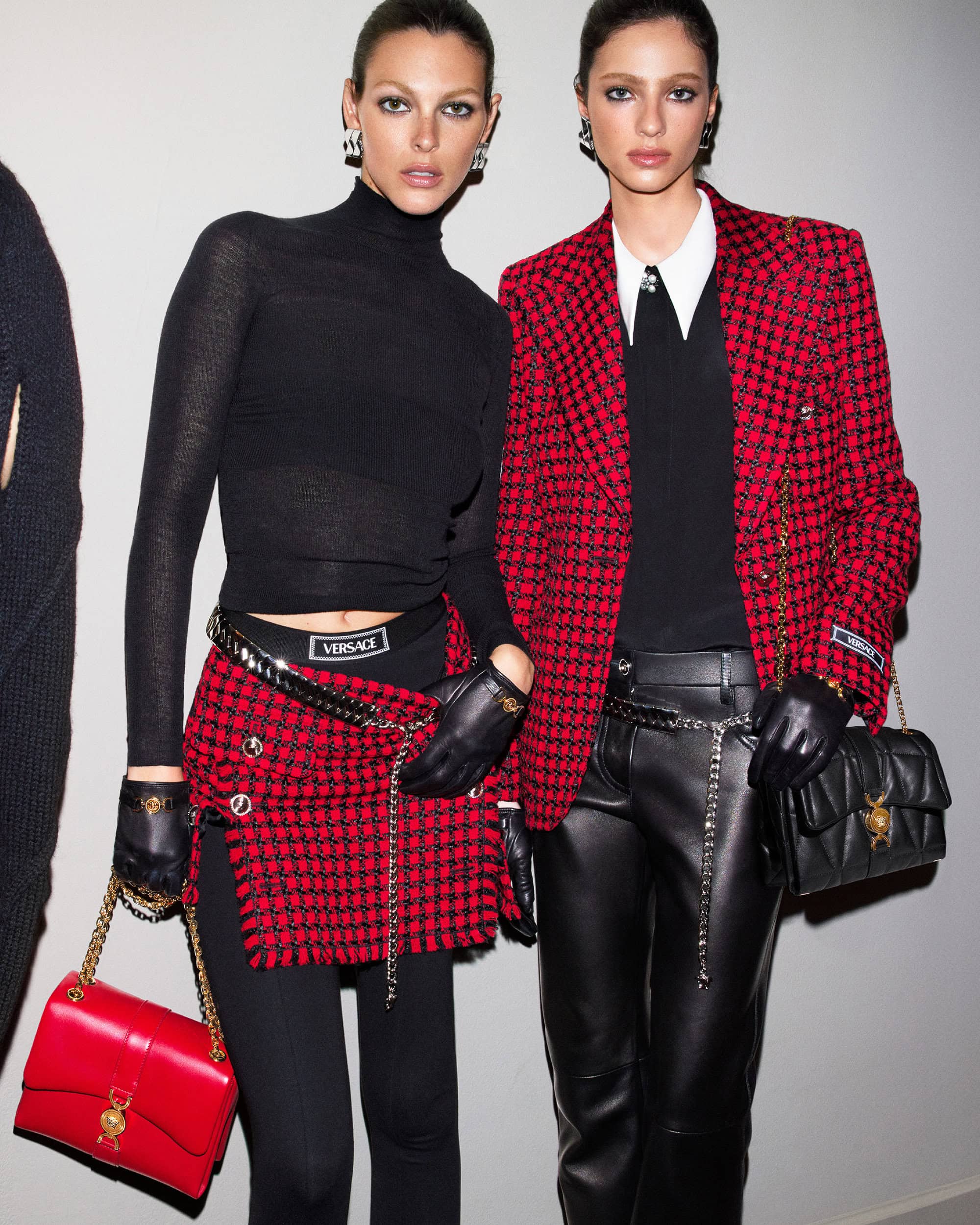 Two female models wearing designer fashion outfits with red tweed and black leather, photographed by Mert and Marcus for Versace.