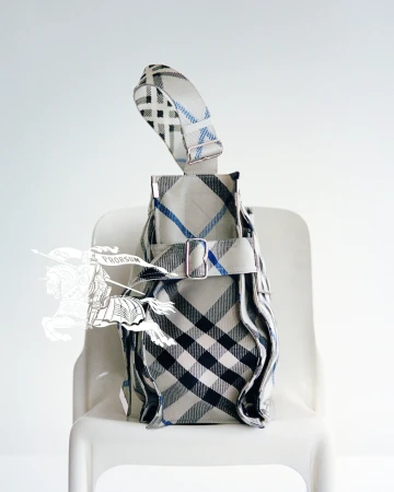 Burberry plaid handbag resting on a white chair against a plain white background with a faint equestrian knight logo.