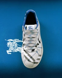 Top-down view of a Burberry plaid sneaker on a solid blue surface with a white knight logo overlay.