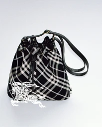 Burberry black and white plaid bucket bag with black leather strap against a clean white background