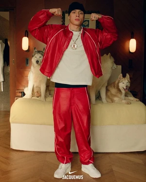 Central Cee in a red jacket and matching pants posing in front of a bed with huskies for Jacquemus x Nike