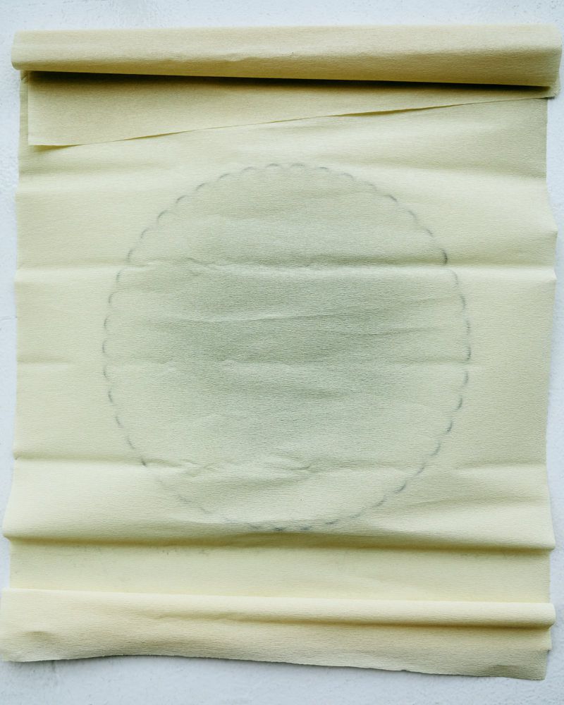 Close-up of rolled parchment paper featuring a faint circular design, creating a textured and artistic background.