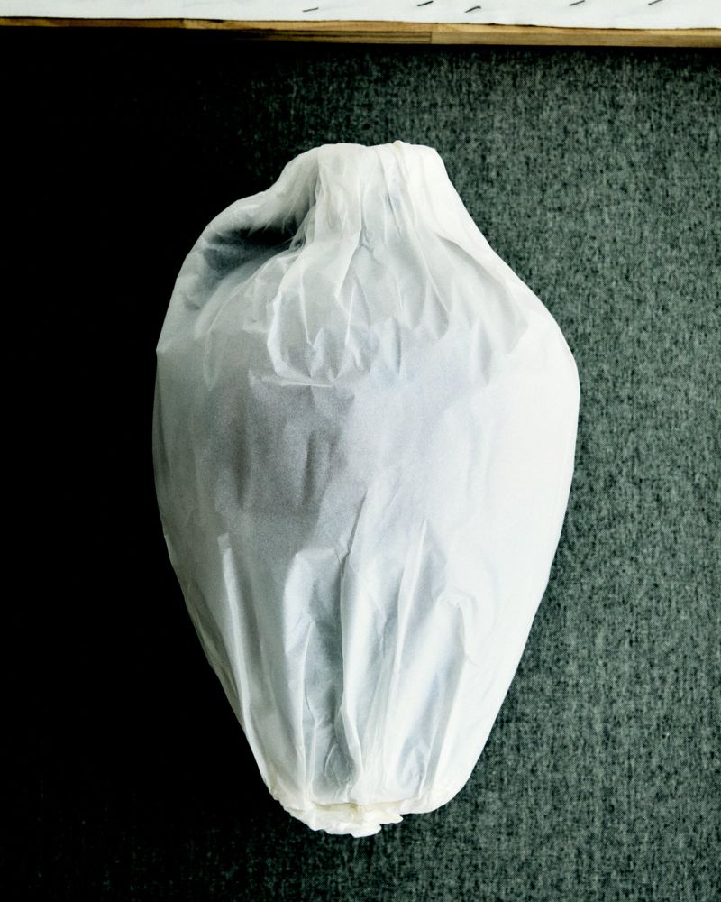 Wrapped object with protective paper, set against a textured background, creating an abstract presentation with layers of packaging.