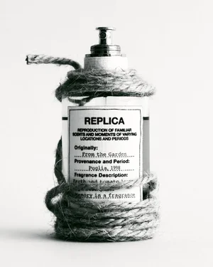 Close up of a glass perfume bottle wrapped tightly in rustic twine against a seamless white background.