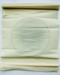 Cream-colored rolled parchment paper with a faint circular scalloped border on a plain background