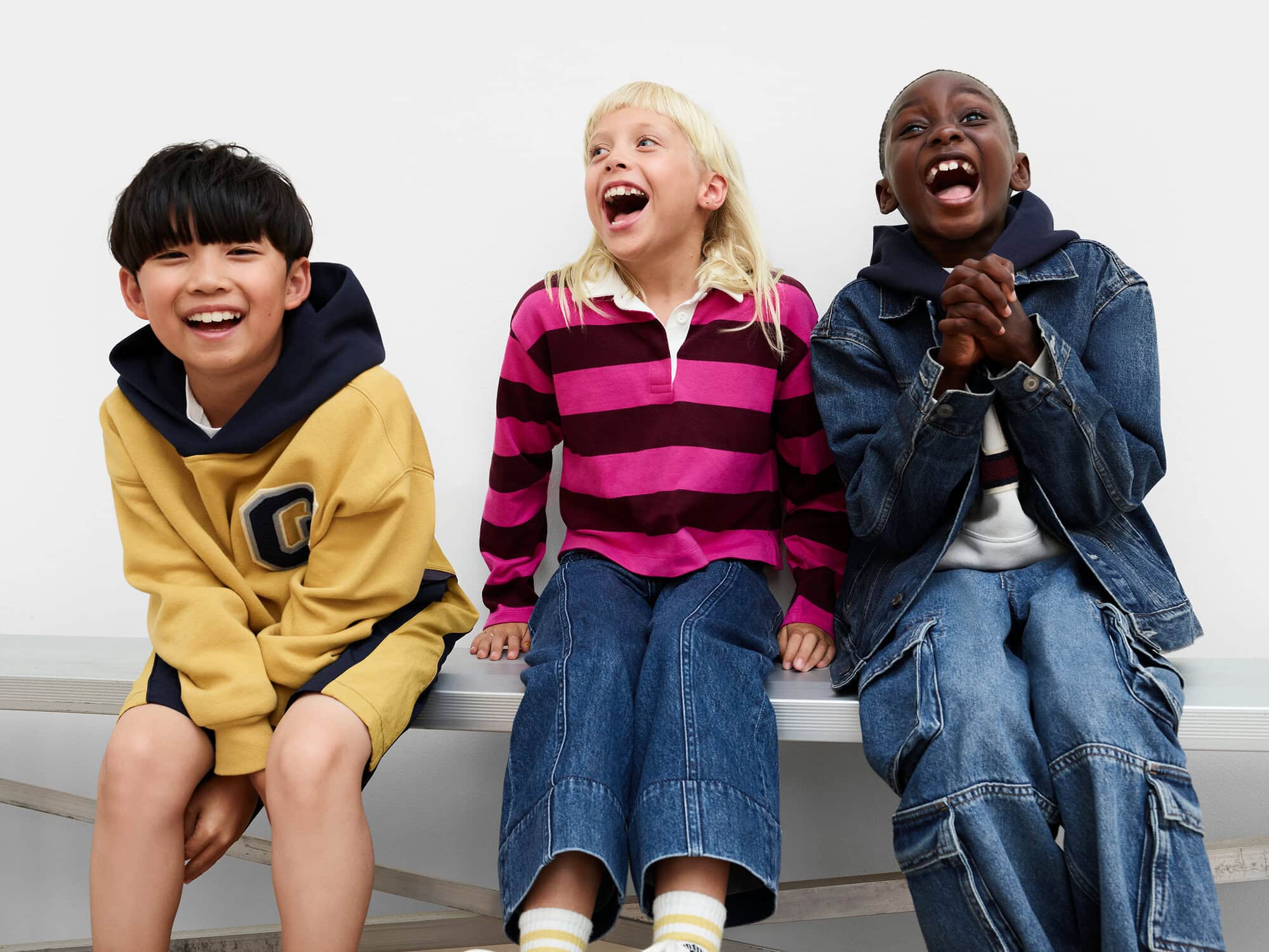 Three children laughing on a bench against a white background for the Gap Just dance ad campaign.