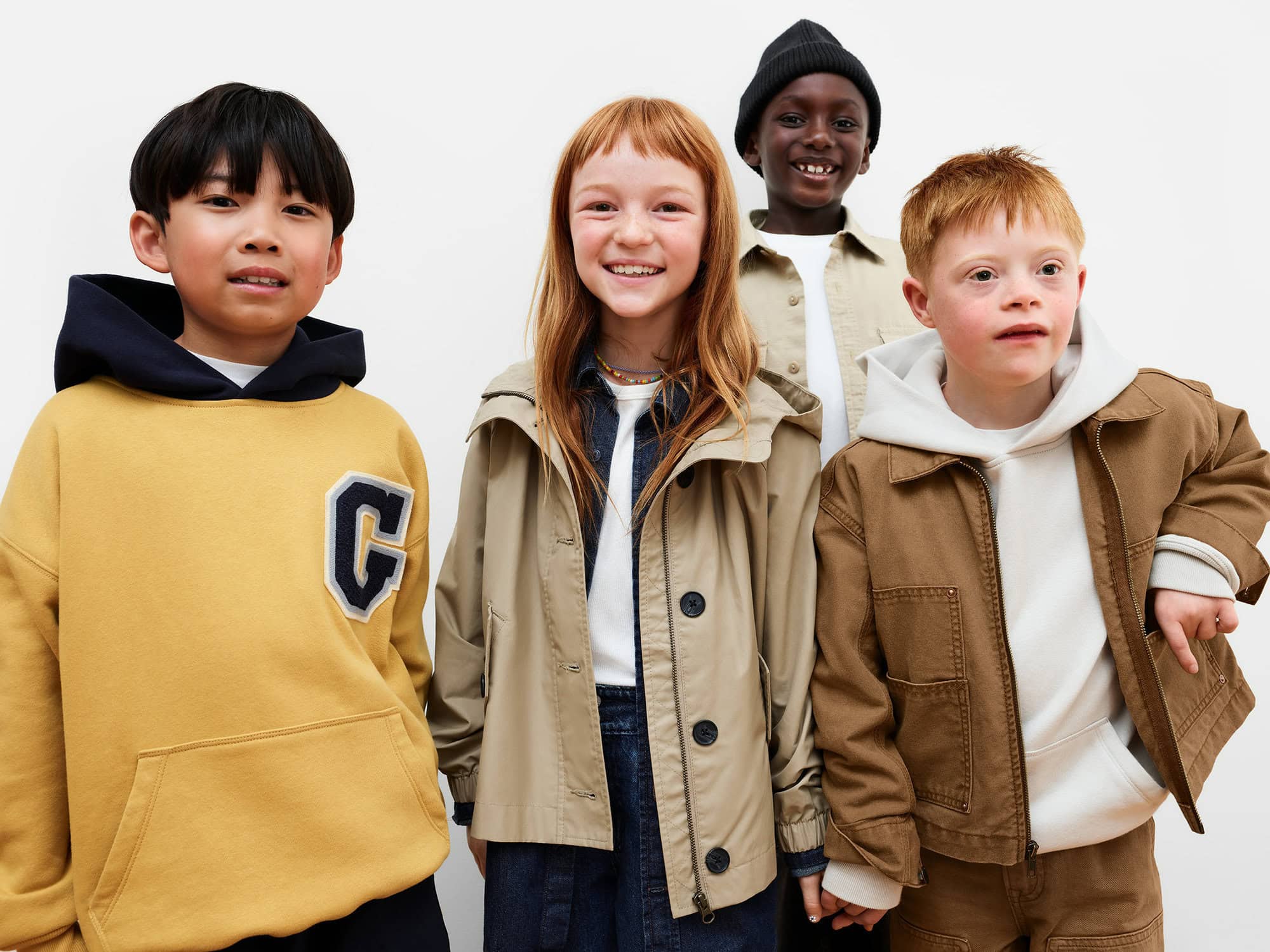 Four children smiling against a plain white background wearing casual jackets and hoodies for Gap Just Dance campaign