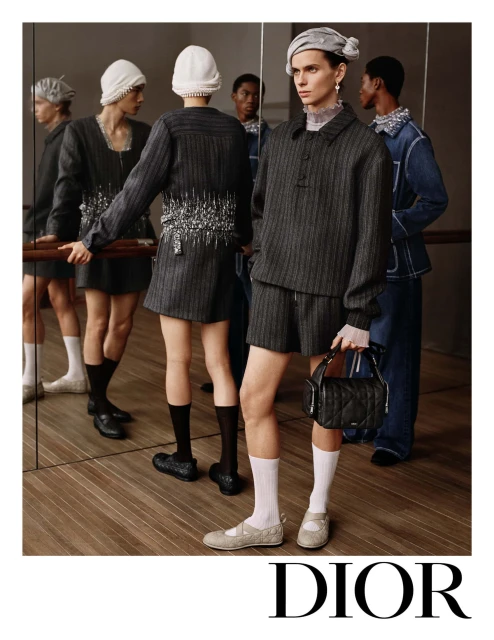 Fashion editorial featuring a group of models wearing elegant grey and white ensembles in an indoor setting with soft lighting.